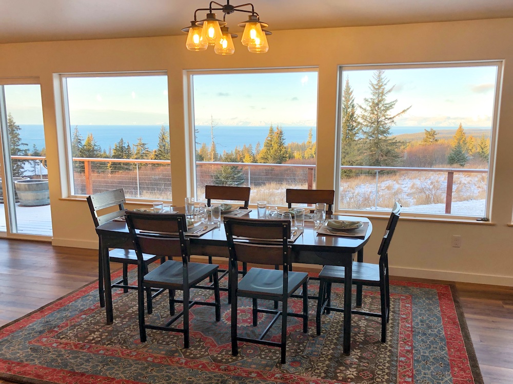 Table set in front of a window with forests and sea.